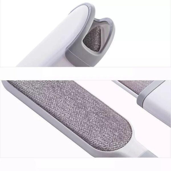 Imagen en primer plano de un removedor de pelo para mascotas con un cepillo reutilizable de doble cara con una superficie gris texturizada. El mango de plástico blanco tiene un borde gris y una base autolimpiante con una muesca en forma de corazón para facilitar la inserción del cepillo.