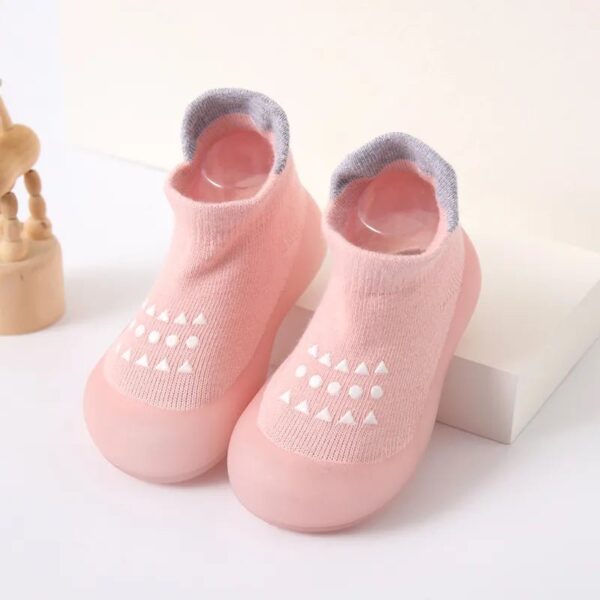 Un par de lindos botines de niño de color rosa sobre una superficie blanca, con un diseño suave y acogedor, perfecto para pies pequeños.