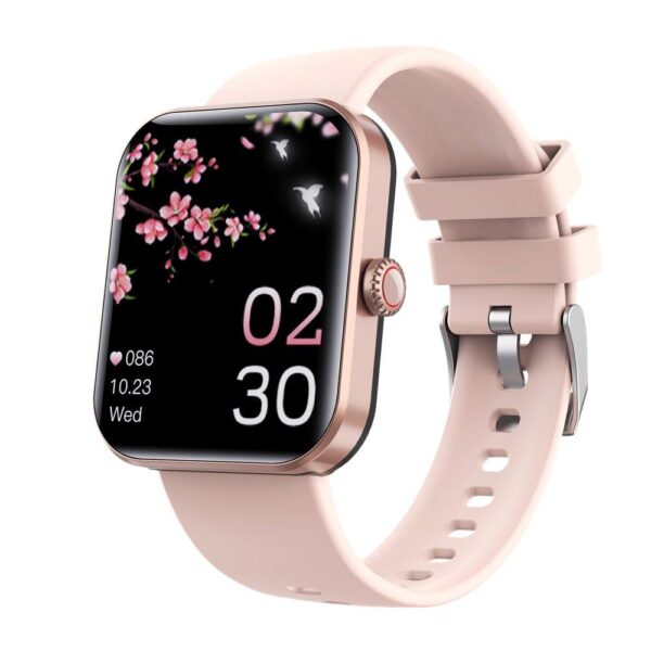 A smart watch with a pink strap displaying a digital watch face with pink cherry blossoms, a hummingbird, and the time 02:30. The background is black, and the watch shows date and heart rate information. The watch has a rectangular screen and a side button.